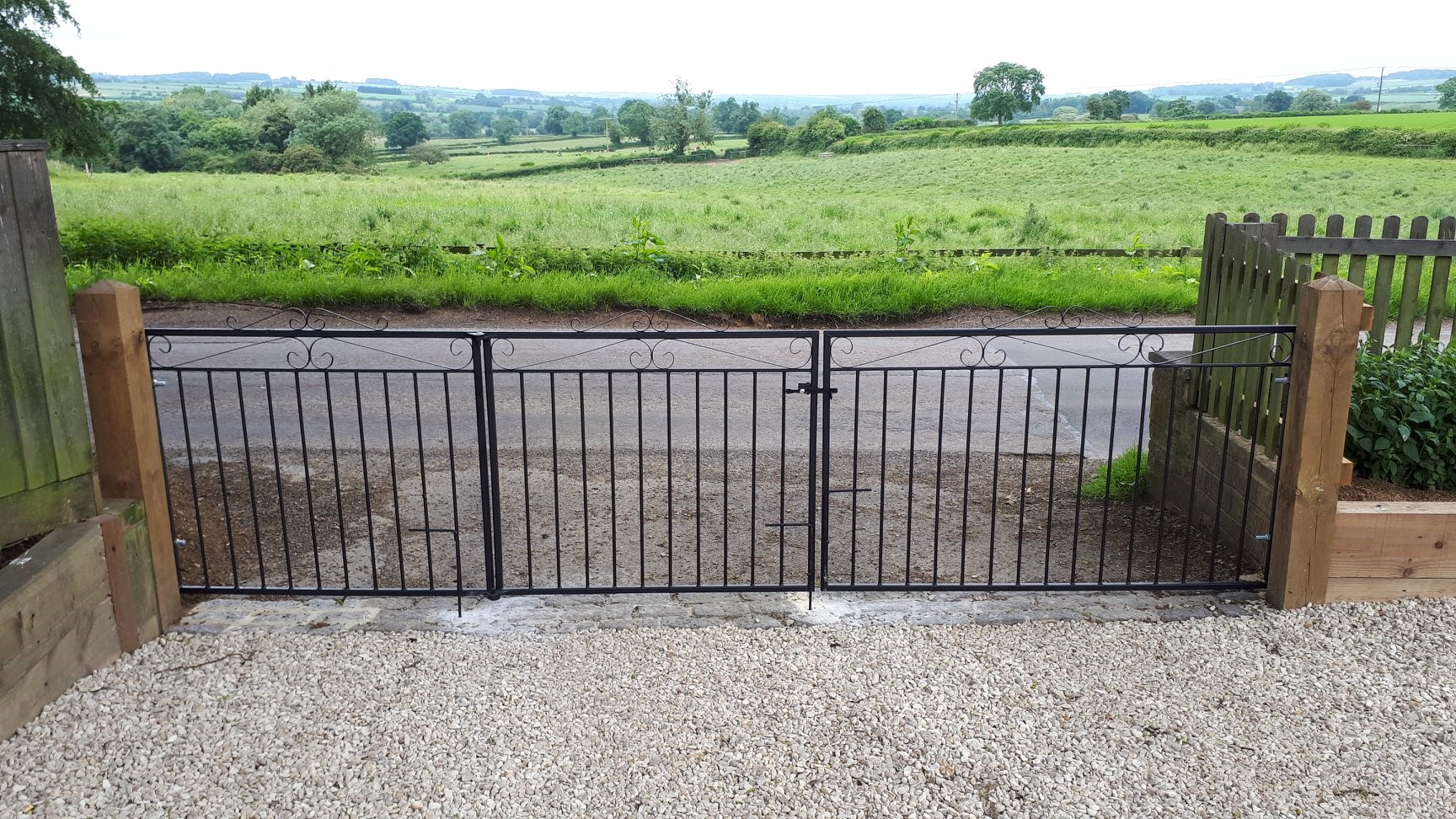 bi folding triple gates with a sloping driveway