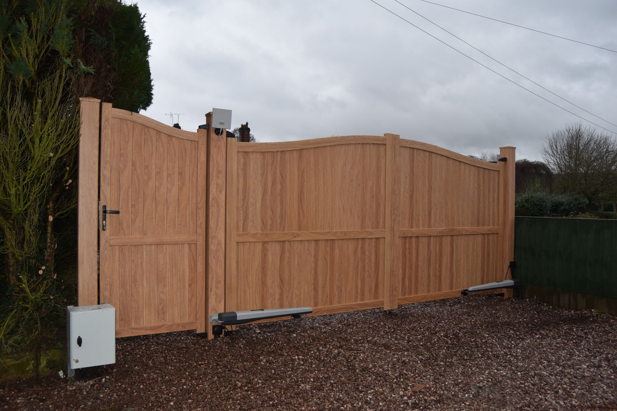 Double aluminium drive gates and matching side gate painted in woodgrain effect light oak finish