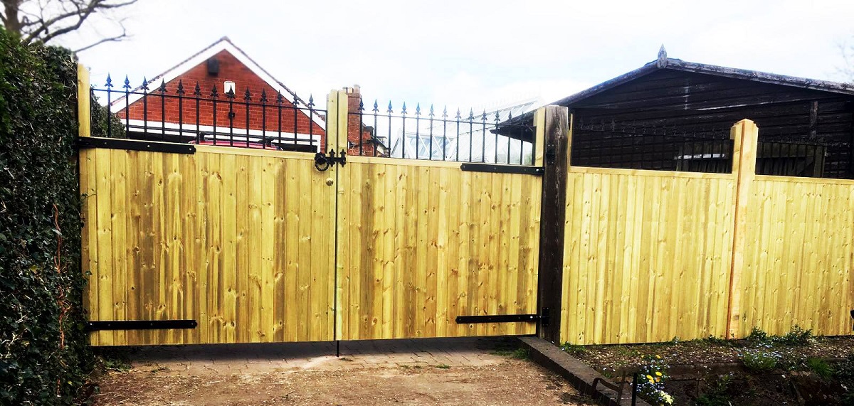 Bespoke double wooden driveway gates fitted to detached surrey property with matching fence panels