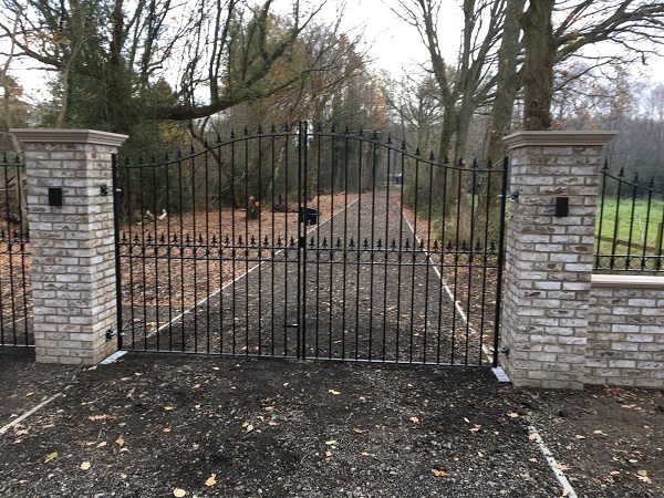 Wrought iron style driveway gate mounted onto brick pillars