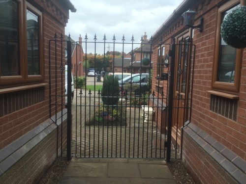 Hampton wrought iron side gate with metal infill panels securing passageway