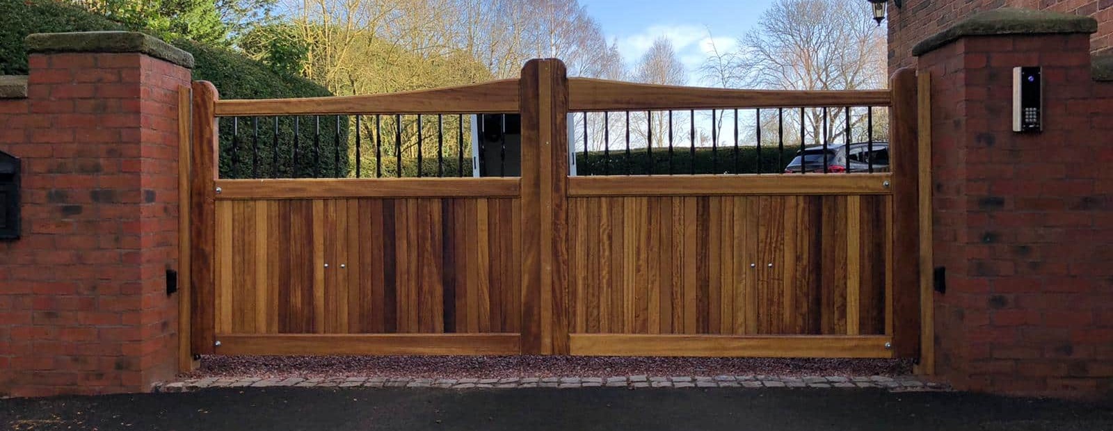Iroko slope top double driveway gates with twisted metal spindles