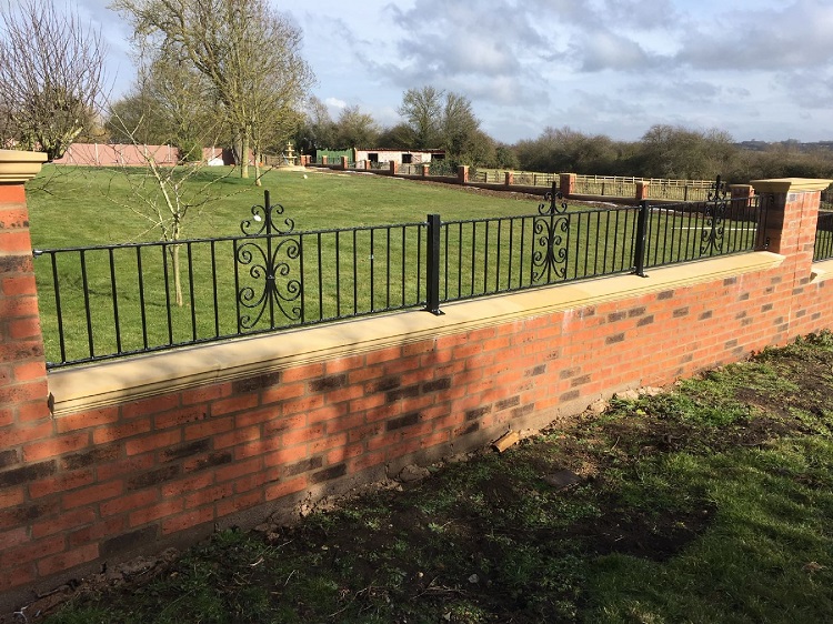 Metal garden railings fitted to the top of a brick boundary wall