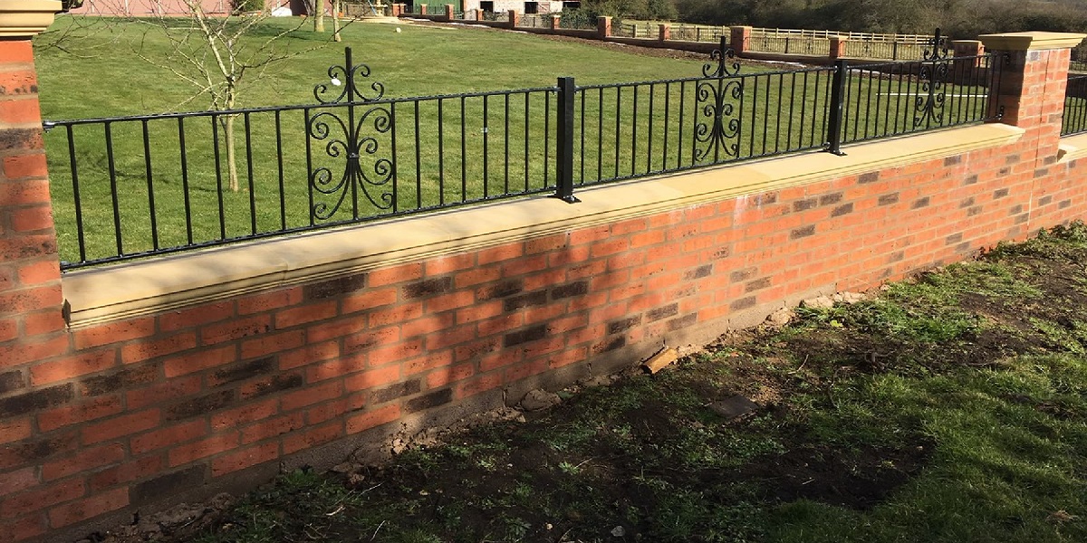 Bespoke wrought iron garden fencing mounted to brick wall